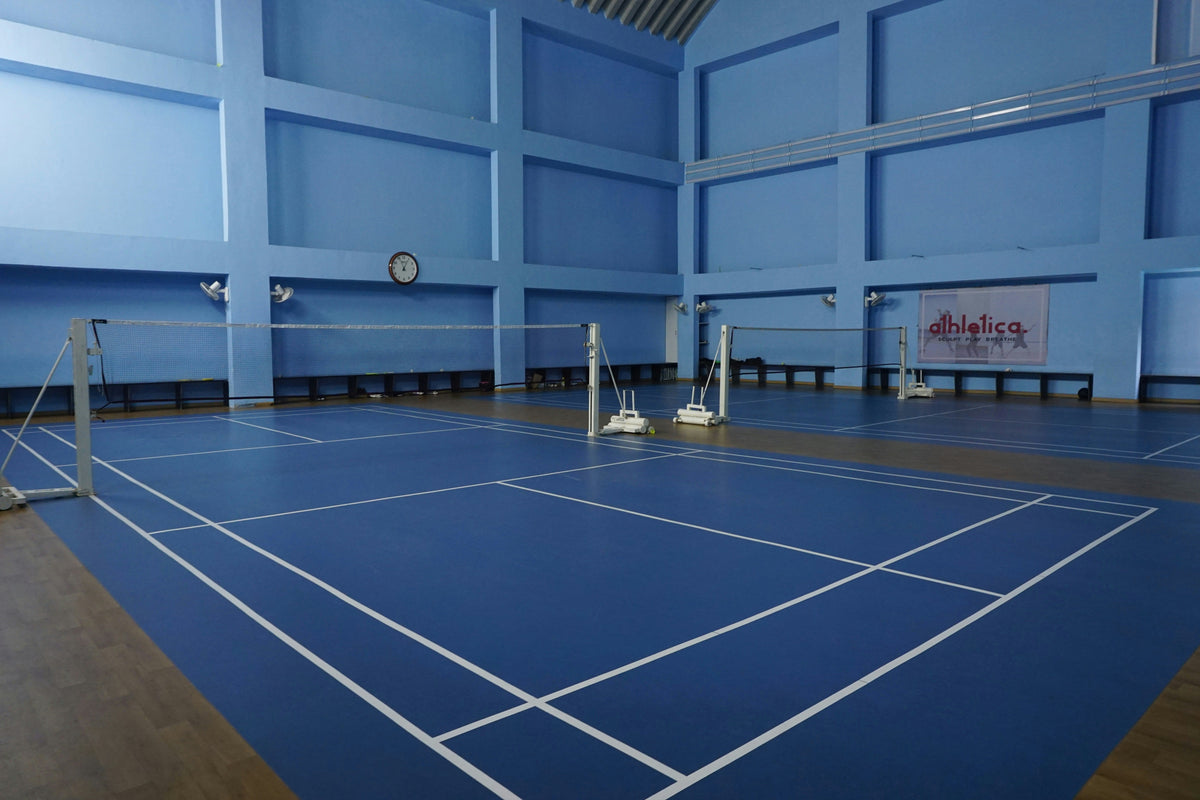 Indoor badminton hall with blue courts, nets and overhead lighting